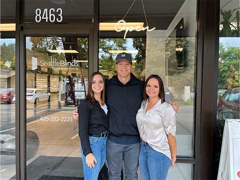 A small family standing close together by the storefront