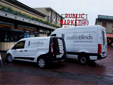 Two white company vans with the Seattle Blinds logo