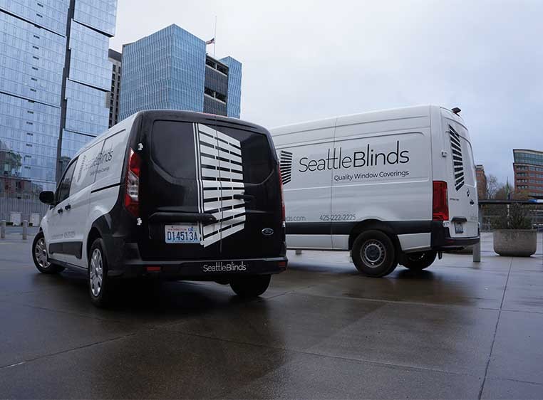 Two white company vans with the Seattle Blinds Logo